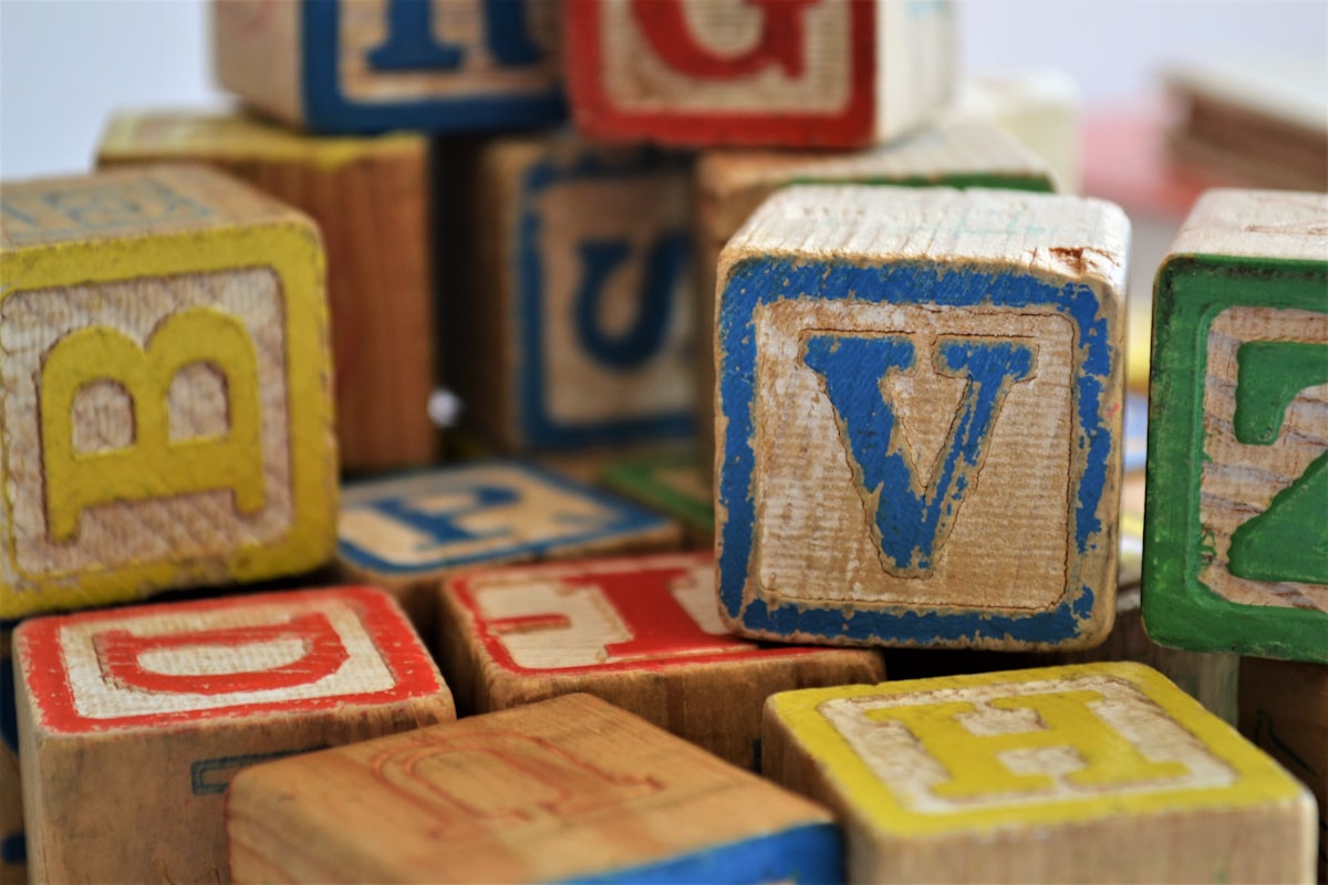 Blocos de madeira com letras, cantos gastos e cores vermelho, amarelo e azul